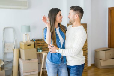 Genç çift yeni bir eve hareket, yeni dairenin anahtarlarını gösteren aşk sarılmak çok mutlu gülümseyen