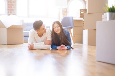 Genç Asya çift yatıyor üzerinde bu zemin bu yeni ev civarı karton kutular rahatlatıcı ve gülümseyen mutlu