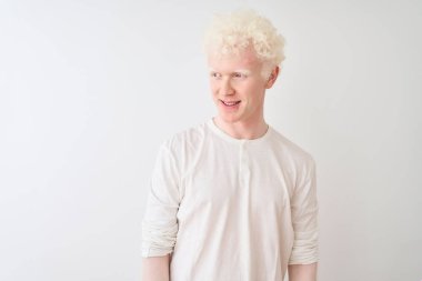Genç albino sarışın adam izole beyaz arka plan üzerinde duran rahat t-shirt giyen yüzünde gülümseme, doğal ifade ile yan bakıyor. Gülmekten emin.