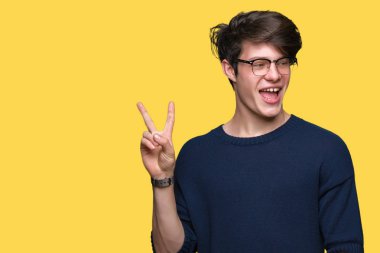 Mutlu yüz zafer işareti yaparken kameraya göz kırpıyor ile gülümseyen izole arka plan üzerinde gözlük takan yakışıklı delikanlı. İki numaralı.