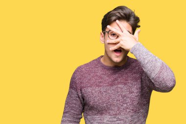 Mahcup ifadeyle parmaklarımın arasından seyir yüz ve gözler el ile kapsayan şok bakmak izole arka plan üzerinde gözlük takan genç yakışıklı adam.