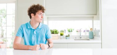 Evde yan bakarak genç yakışıklı adam geniş çekim, kendine güvenen gülümseme ile doğal yüzü ile profil poz dinlenmek.