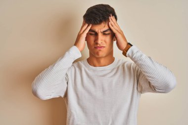 Genç hintli adam izole beyaz arka plan üzerinde ayakta kazak giyen baş ağrısı umutsuz muzdarip ve stresli çünkü ağrı ve migren. Eller baş üstünde.