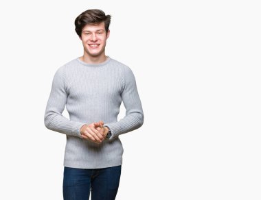 Arka plan eller üzerinde kış kazak giyen genç yakışıklı adam birlikte izole ve rahat ve neşeli gülümseyen parmak çarpı işareti. Başarı ve iyimser