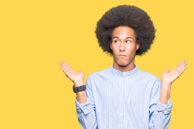 Afrikalı-Amerikalı genç afro saç clueless ve şaşkın bir ifadeyle kollar ve eller kaldırdı ile. Şüphe kavramı.