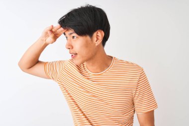 Izole beyaz arka plan üzerinde duran rahat çizgili t-shirt giyen genç Çinli adam çok mutlu ve başının üzerinde el ile uzak görünümlü gülümsüyor. Arama konsepti.