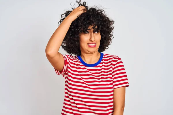 孤立した白い背景の上にストライプのTシャツを着て巻き毛を持つ若いアラブの女性は混乱し 質問について不思議に思います 頭の上に手を置いて考え 疑いを持って不確か ペンシブコンセプト — ストック写真
