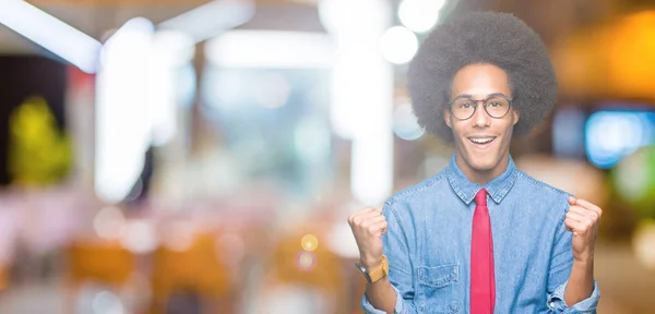 若いアフリカ系アメリカ人ビジネスの男性眼鏡と赤いアフロの髪と腕を上げると 驚きと驚きの成功を祝ってのネクタイし 目を開きます 勝者の概念 — ストック写真