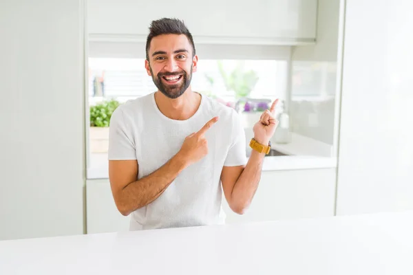 ハンサムなヒスパニック系男性ホーム笑顔と側に つの手と指で指しているカメラ目線で白い シャツ カジュアル — ストック写真