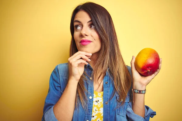 Young Beautiful Woman Eating Fresh Healthy Mango Yellow Background Serious — Stock Photo, Image