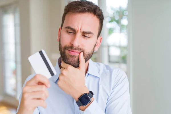 Bonito Homem Negócios Segurando Cartão Crédito Rosto Sério Pensando Questão — Fotografia de Stock