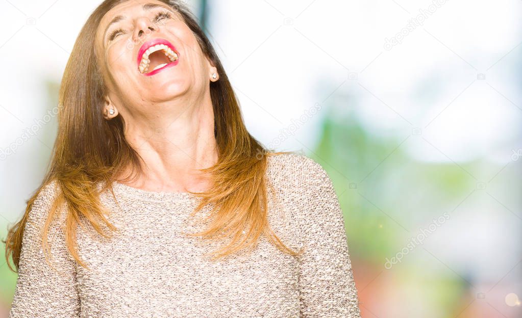 Beautiful middle age woman wearing fashion sweater Smiling and laughing hard out loud because funny crazy joke. Happy expression.