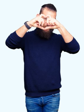 Gözlük ve balıkçı yaka kazak yapıyorsun kalp şekli ile el ve parmak işareti seyir gülümseyen giyen genç sarışın adam