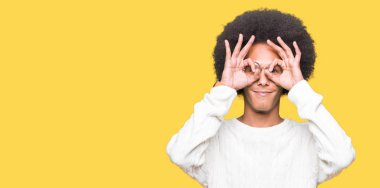 Afrikalı-Amerikalı genç afro saçlı gözlüklü, dilini parmaklarının arasından baktığını yapışmasını dürbün gibi ok jest yapıyor. Deli ifade.