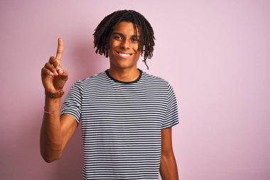 Dreadlocks lacivert çizgili t-shirt giyen afro adam izole pembe arka plan üzerinde duran gösteren ve emin ve mutlu gülümserken parmak sayısı bir işaret.