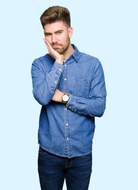 Young handsome blond man wearing casual denim shirt thinking looking tired and bored with depression problems with crossed arms. clipart