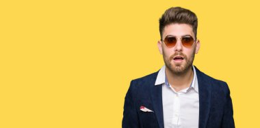 Genç yakışıklı zarif adam gözlük ve moda Blazer korkuyor ve sürpriz ifade, korku ve heyecanlı yüz ile şok giyiyor.