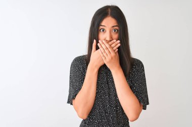 İzole beyaz arka plan üzerinde duran zarif t-shirt giyen genç Çinli kadın hata için elleri ile ağız kapsayan şok. Gizli kavram.