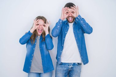 Genç güzel çift beyaz izole arka plan üzerinde birlikte duran dürbün dil dışarı yapışmasını gibi ok jest yapıyor, gözleri parmaklardan bakarak. Çılgın ifade.