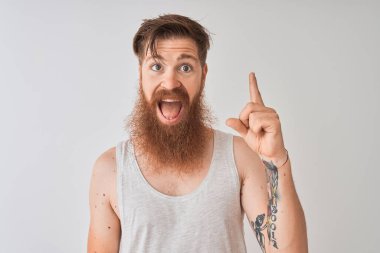 Genç Redhead İrlandalı adam izole gri arka plan üzerinde ayakta t-shirt giyerek başarılı bir fikir parmak yukarı işaret. Çıkıldı ve mutlu. Bir numara.