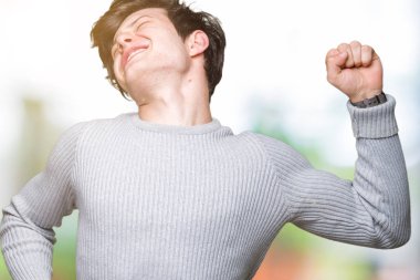 Üzerinde kış kazak giyen genç yakışıklı adam arka plan geri uzanan izole, yorgun ve rahat, Uykulu ve erken sabah esneme