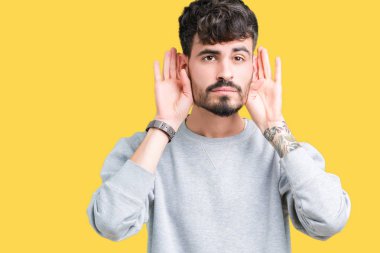 Her ikisi de dinliyoruz izole arka plan üzerinde sweatshirt giyen genç yakışıklı adam kulak jest, dedikodu için meraklı eller. İşitme sorunu, sağır