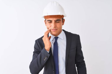 Genç yakışıklı mimar adam izole beyaz arka plan üzerinde takım elbise ve kask giyen diş ağrısı veya diş üzerinde diş hastalığı nedeniyle ağrılı ifade ile el ile ağız dokunmadan. Diş hekimi konsepti.