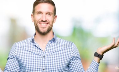 Yakışıklı iş adamı mavi ile gösterilen iki elin avuç içi açık, sunma ve karşılaştırma ve denge reklam gülen gözler