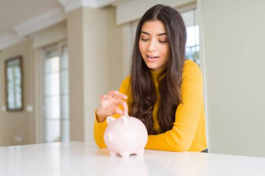 Yatırım olarak Piggy banka içinde bir sikke koyarak gülümseyen kadın yakın