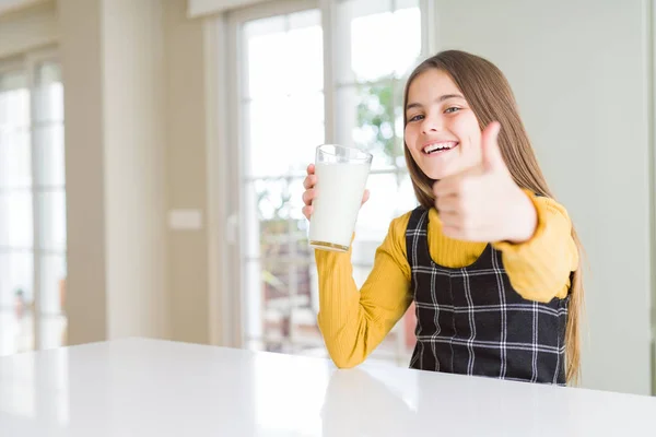 美丽的年轻女孩抚摸着一杯鲜奶高兴 大笑着做Ok标志 竖起大拇指用手指 优秀的标志 — 图库照片