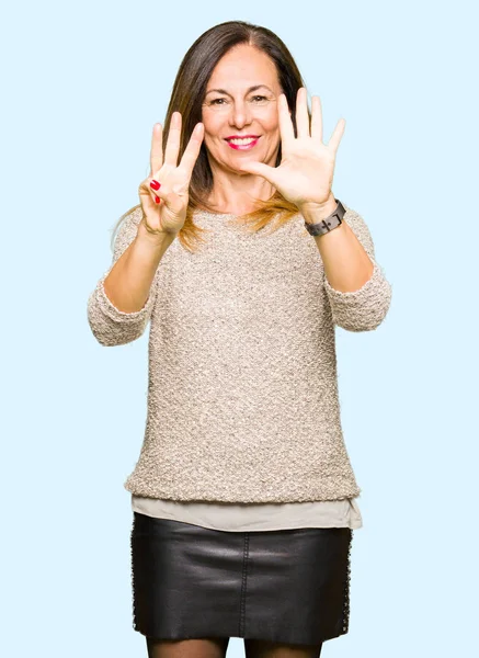 Güzel orta yaş kadın giyiyor moda kazak gösterme ve parmakları ile işaret kendinden emin ve mutlu gülümseyerek süre sekiz numara.