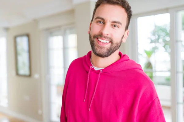 Hombre guapo vistiendo sudadera casual en casa y sonriendo — Foto de Stock