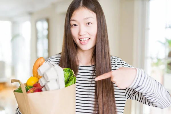 新鮮な食料品の紙袋を持つ美しいアジアの女性は 手と指で指差し非常に幸せ — ストック写真