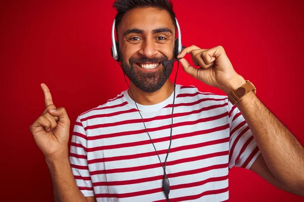 孤立した赤い背景の上にヘッドセットを使用する若いインドのコールセンターエージェントの男は 側に手と指で指で非常に幸せ — ストック写真
