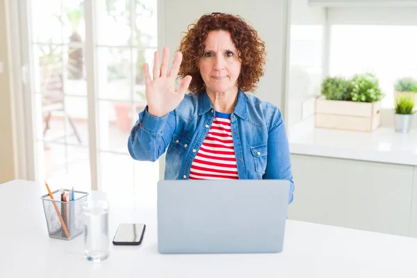 使用电脑笔记本电脑工作的高级妇女张开手做停止标志 用严肃和自信的表情 防御手势 — 图库照片