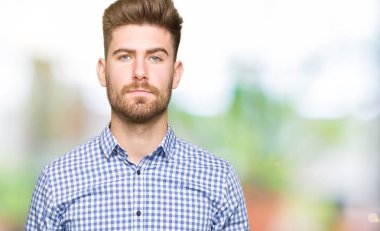 Genç yakışıklı bussines adam yüzünde ciddi bir ifade ile. Basit ve doğal kameraya bakıyor.