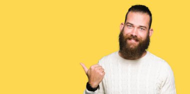 Seyir ve başparmak yanında yukarıyı mutlu yüz ile gülümseyen kış kazak giyen genç hipster adam.