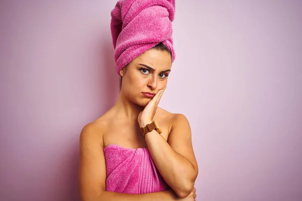 孤立したピンクの背景の上にシャワーの後にタオルを身に着けている若い美しい女性は 腕を組んだうつ病の問題に疲れて退屈しているように見えます — ストック写真