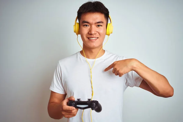 年轻的亚洲中国玩家男子玩视频游戏站在孤立的白色背景与惊喜的脸指向自己 — 图库照片