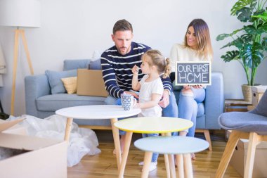 Karton kutular etrafında yeni evde kara tahta tutan kanepede oturan çocuk ile güzel famiily