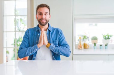 Yakışıklı adam evde elleri birlikte dua güvenle gülümseyerek af dileyen.