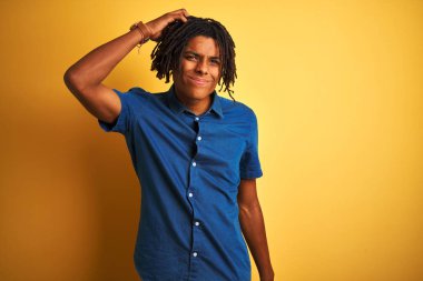 Izole sarı arka plan üzerinde duran rahat kot gömlek giyen dreadlocks ile Afro adam karıştırmayın ve soru hakkında merak ediyorum. Şüpheyle belirsiz, eliyle kafada düşünmek. Pensive kavramı.