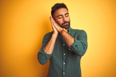 Genç hintli işadamı izole beyaz arka plan üzerinde duran zarif gömlek giyen yorgun rüya ve kapalı gözlerle gülümseyerek birlikte elleri ile poz.