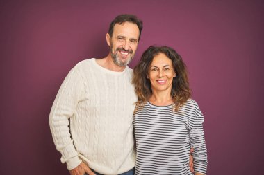 Güzel orta yaş çift yüzünde mutlu ve serin bir gülümseme ile izole mor arka plan üzerinde kış kazak giyiyor. Şanslı kişi.