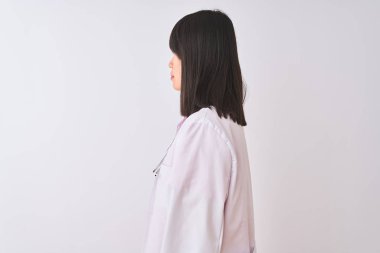 Genç güzel Çinli doktor kadın izole beyaz arka plan üzerinde stetoskop giyen yan bakarak, kendine güvenen gülümseme ile doğal yüz ile profil poz dinlenmek.