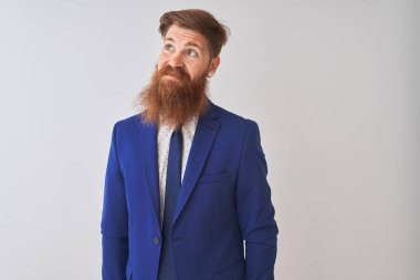 Genç kızıl saçlı İrlandalı işadamı takım elbise giyen izole beyaz arka plan üzerinde yan bakarak gülümseyerek ve düşünme uzak bakıyor.