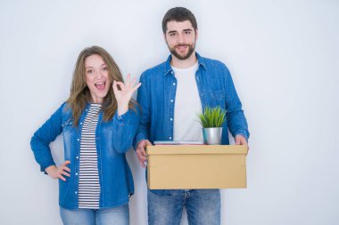 Genç çift parmakları, mükemmel sembolü ile ok işareti yapıyor beyaz izole arka plan üzerinde yeni eve hareket karton kutu tutan