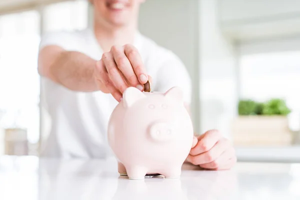 Close up of man putting a coin inside piggy bank as saving or in — Stock Photo, Image