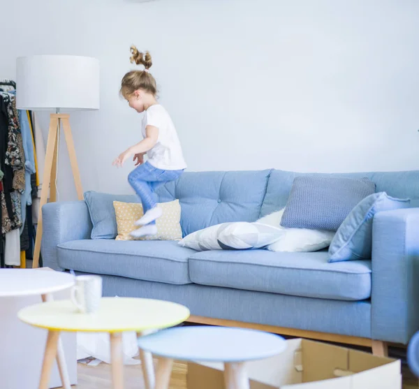 Beautiful toddler child girl jumping on the sofa