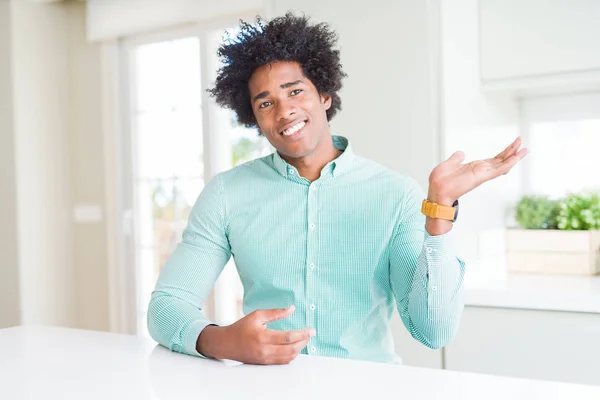 African American business man wearing elegant shirt smiling cheerful presenting and pointing with palm of hand looking at the camera.